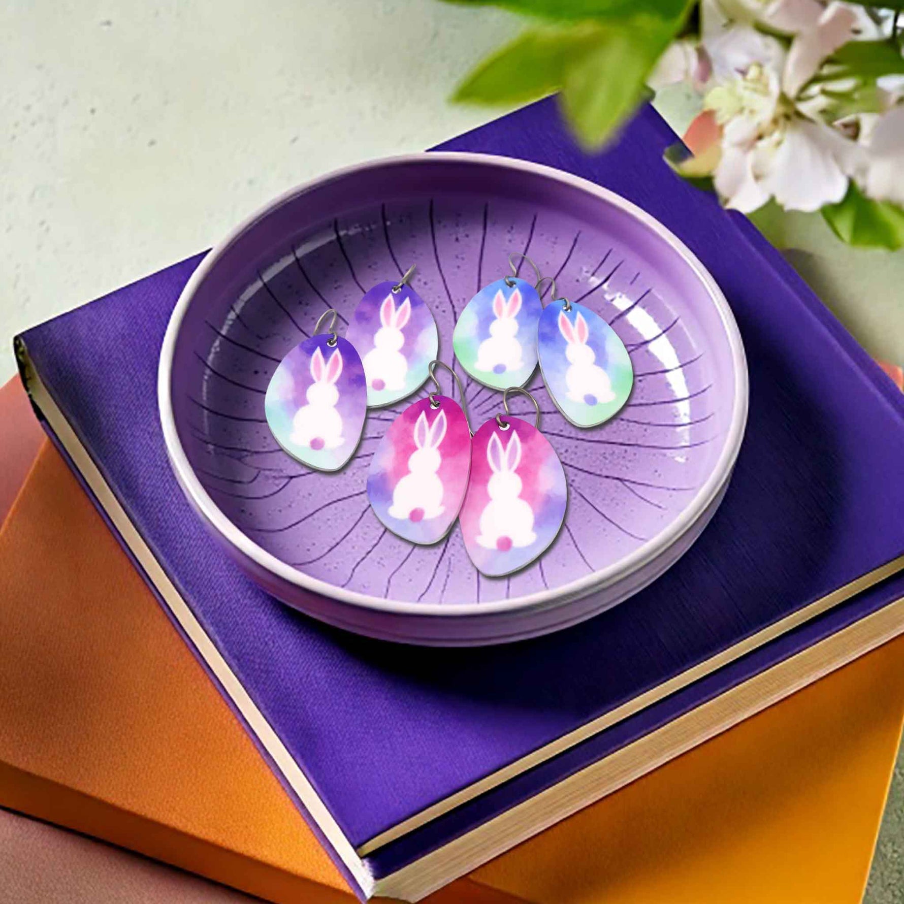 Three pairs of white bunny dangle earrings laying in a purple jewelry dish by ColorUpLife.