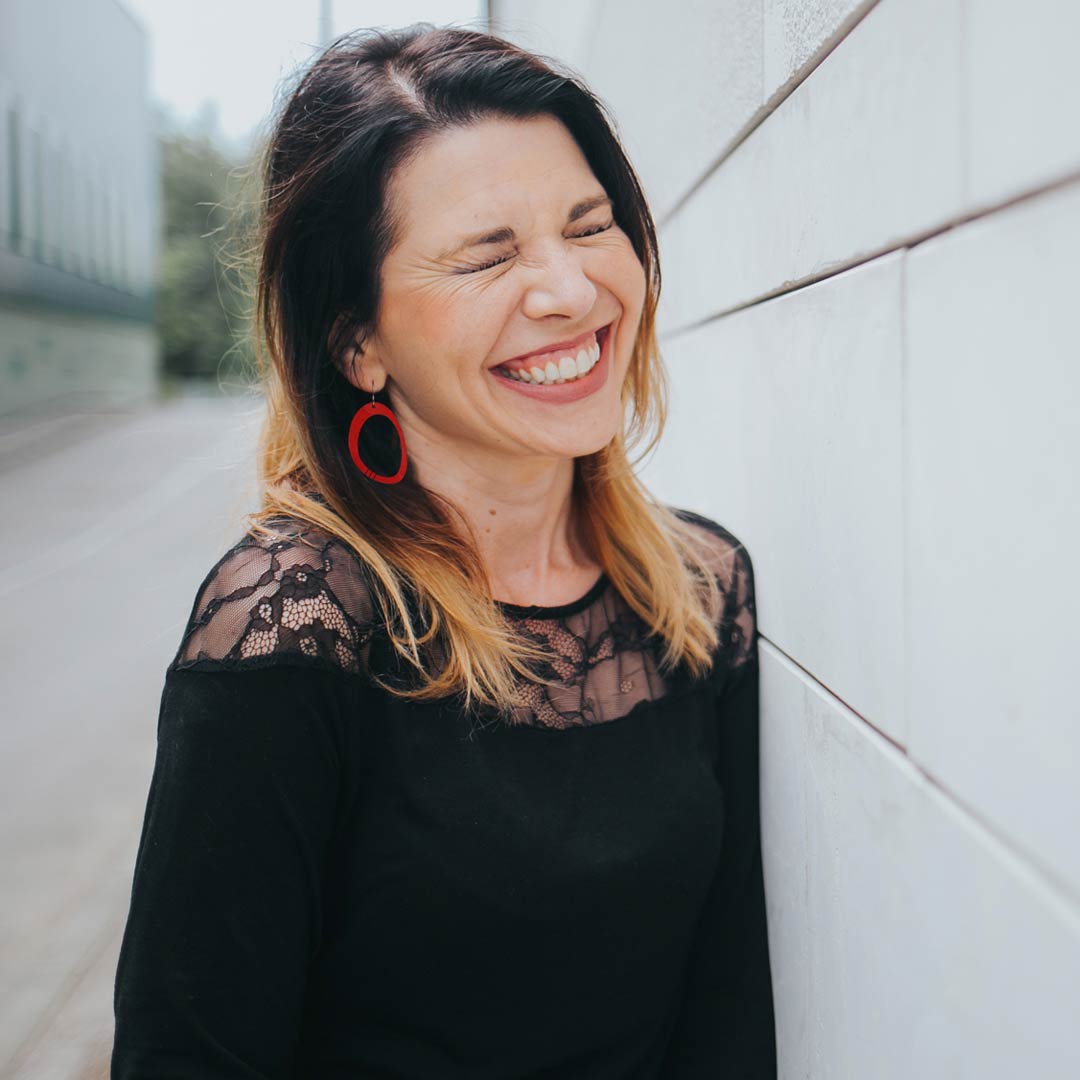 Happy woman wearing large oval hoop dangle earrings in red with black stripes by ColorUpLife.