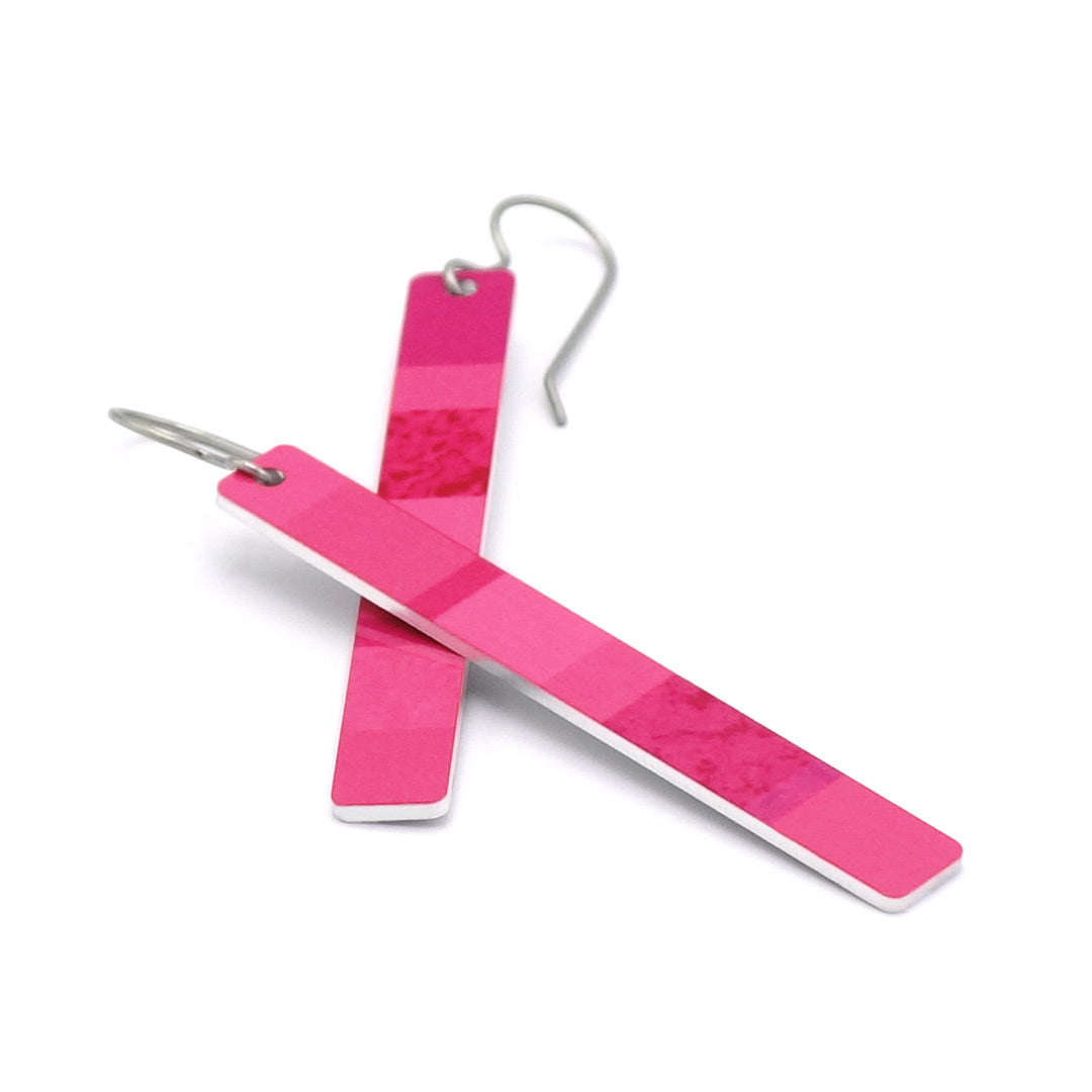 A pair of modern bar earrings in vibrant pink with a subtle marbled pattern, featuring silver-tone titanium fishhook ear wires, displayed on a clean white background.