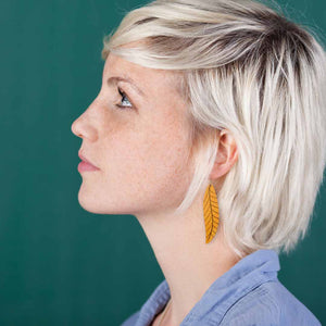 Girl wearing golden yellow, long leaf earrings by ColorUpLife.