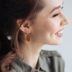 Woman wearing small leaf dangle earrings in brown by ColorUpLife.