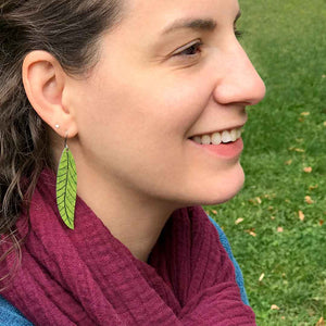 Model wearing long leaf earrings in olive green by ColorUpLife.