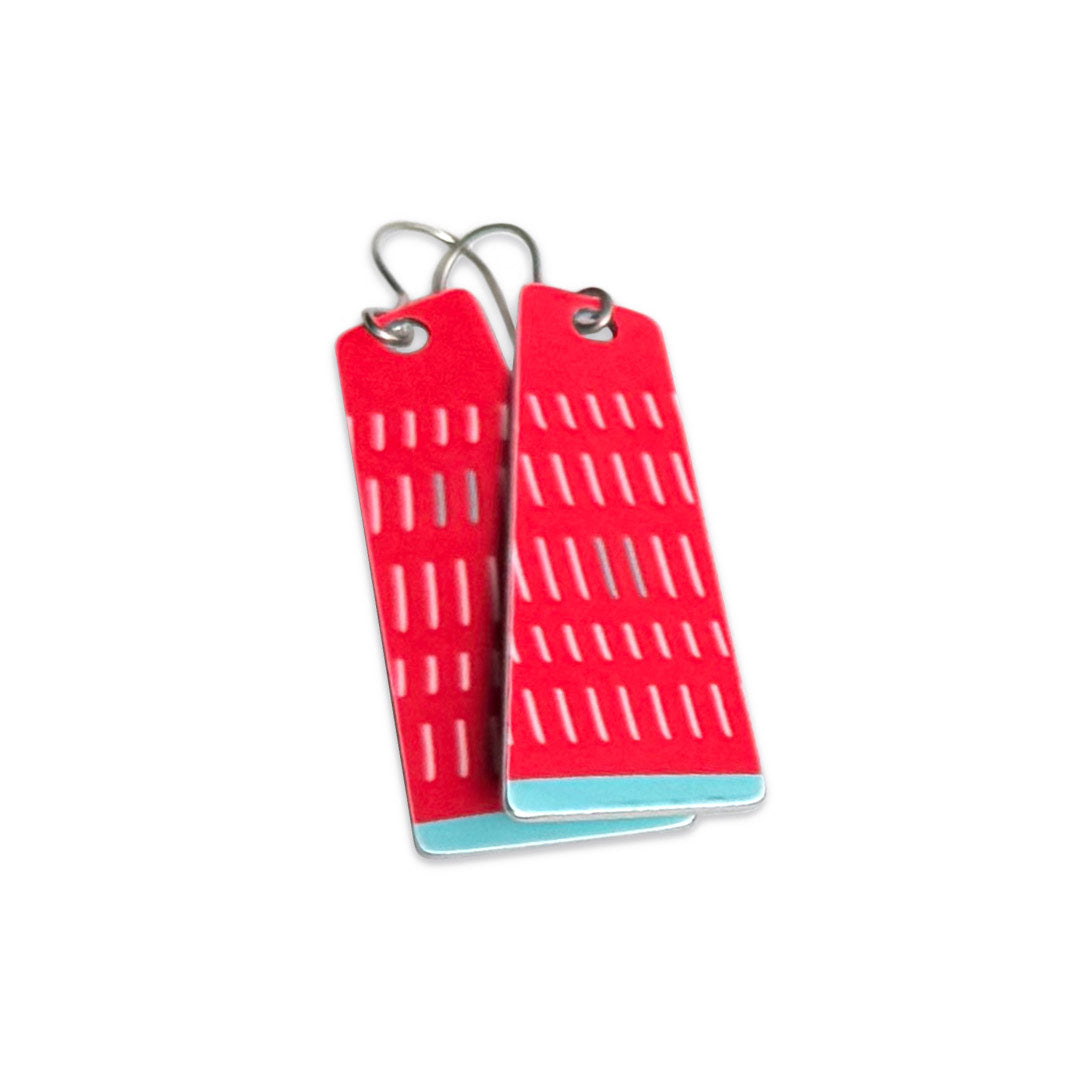 red geometric earrings with a white pattern and teal accents on a white background.