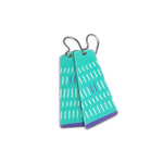 Pair of teal earrings with white and purple line pattern on a white background.