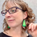 Woman wearing a large pair of Christmas tree dangle earrings by ColorUpLife.