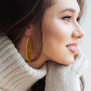 Woman wearing a pair of long brown leaf earrings by ColorUpLife.
