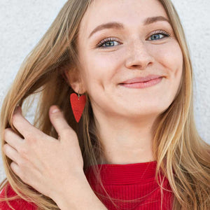 A young women wearing red heart dangle earrings by ColorUpLife